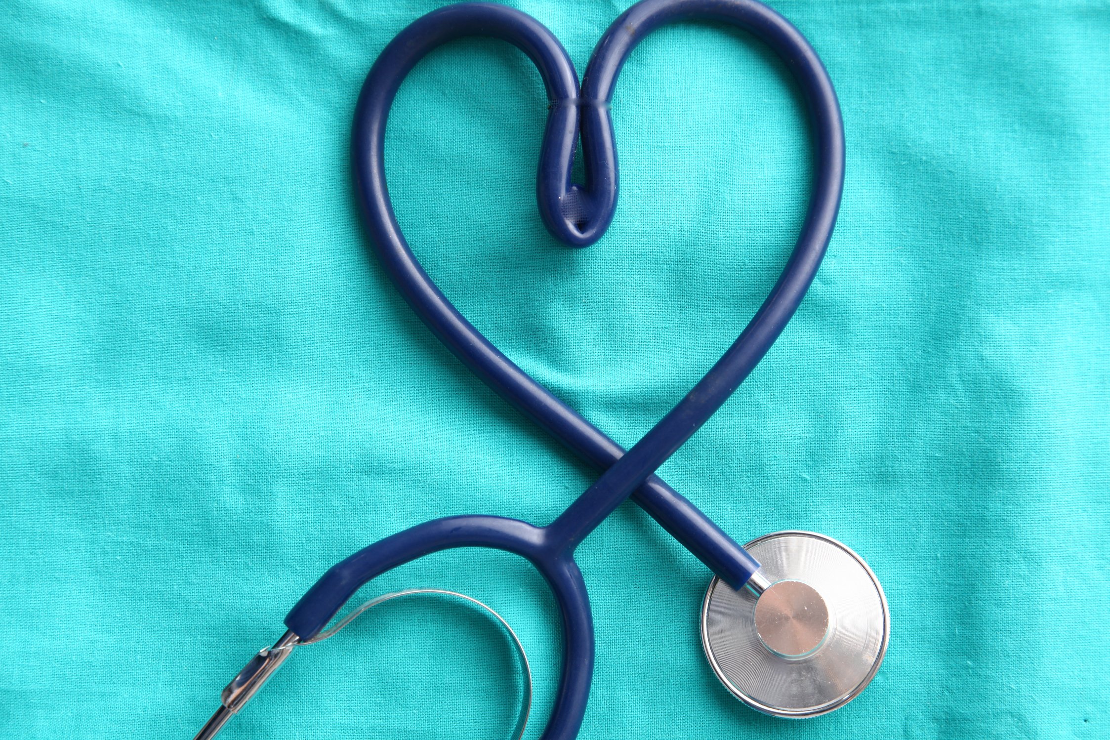 A stethoscope shaping a heart and a clipboard on a medical uniform, closeup